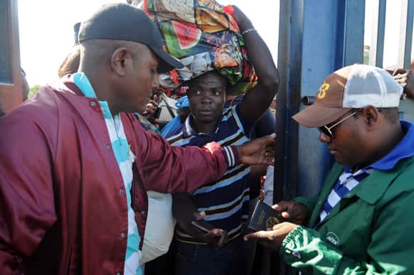 A Haitian worker, center, waits as Dominican police officers check his passport at the northern border crossing with the Dominican Republic in the town of Ouanaminthe, Haiti.