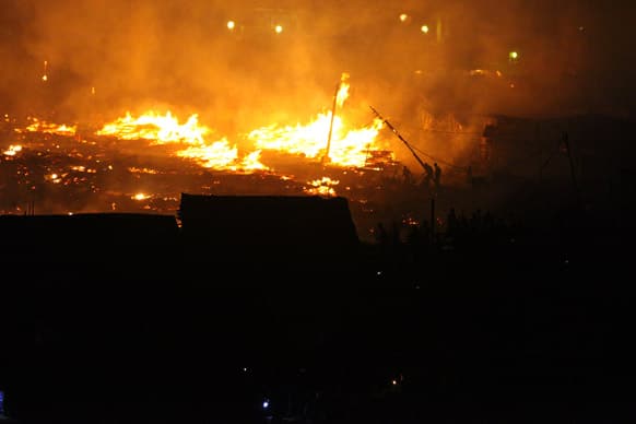 The silhouettes of people can be seen trying to stop a massive fire in Ebute Metta, a neighborhood in Lagos, Nigeria.