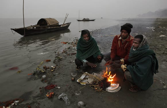 People warm themselves near a fire on a cold and foggy evening near the river Brahmaputra in Gauhati.