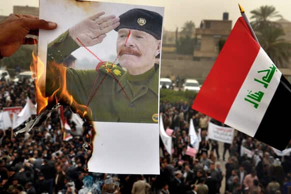 A protester sets fire to a poster of Izzat Ibrahim al-Douri, the highest ranking member of Saddam Hussein`s ousted regime still at large, next to national flag as protesters chant pro-Iraqi Prime Minister Nouri al-Maliki slogans during a demonstration in Basra, Baghdad.