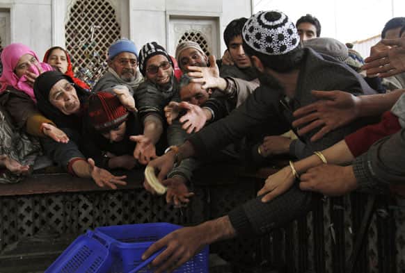 A Kashmiri man distributes bread to other devotees outside the shrine of Sufi saint Hazrat Sheikh Hamza Makhdoom, commonly known as Sultan-Ul-Arifeen, as she offers prayers during the saint`s Urs, or yearly commemoration, in Srinagar.