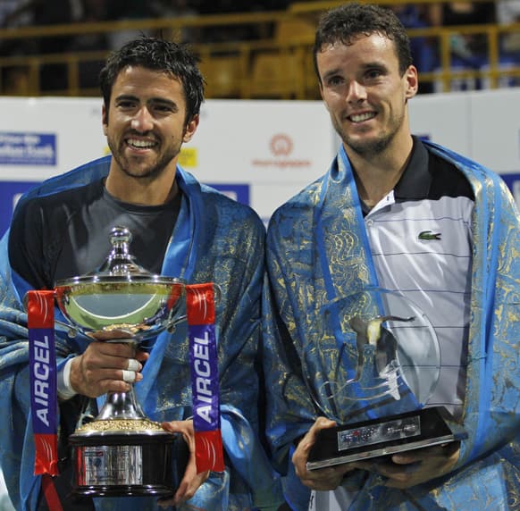 Janko Tipsarevic of Serbia, holds the winner`s trophy after the final match against Roberto Bautista Agut of Spain, right, during the ATP Chennai Open tennis tournament in Chennai.