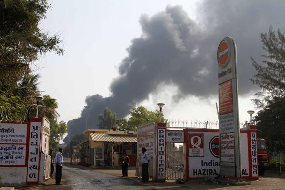 Security men stand at the entrance as smoke rises from a storage tank of the state-owned Indian Oil Corporation (IOC) in Hajira near Surat.