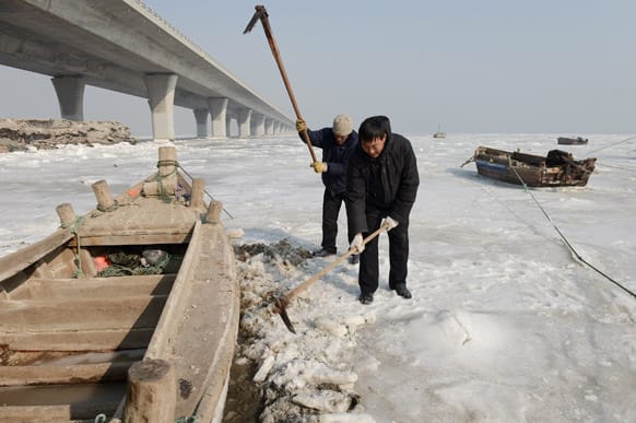 Fishermen try to dig out a fishing boat trapped in ice in the Jiaozhou harbor in Qingdao, in east China`s Shandong province.