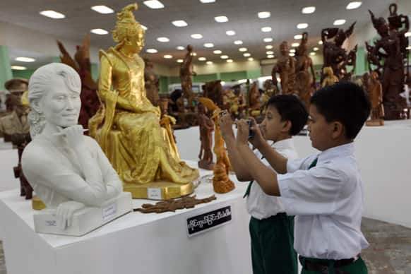 Two boys take photographs of a statue of Myanmar opposition leader Aung San Suu Kyi displayed at the