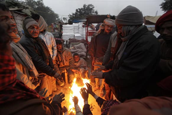 People gather around a bonfire to keep warm on a cold and foggy morning in New Delhi. More than 100 people have died of exposure as northern India deals with historically cold temperatures.