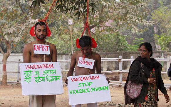 A woman looks at protestors wearing placards as they pretend to be rapists wearing the hangman`s noose in Bhubaneswar.