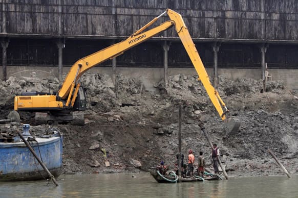 An earthmover removes silt as workers watch from a boat on the banks of the Ganges River in Kolkata. The work is being done to develop the banks of Ganges River as part of a beautification program.