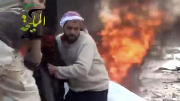 This citizen journalism image taken from video provided by Shaam News Network, shows a wounded man being pulled from the site of a Syrian government airstrike on a gas station in the eastern Damascus suburb of Mleiha, Syria.