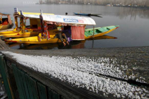 A Kashmiri boatman breaks the frozen surface of the Dal lake as frost is seen at the banks in Srinagar.