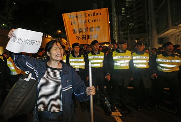 An anti-government protester raises a paper with Chinese words reads ` Police Calm down ` in front of police officers as she blocks a main road in downtown Hong Kong at New Year`s Day to call for the resignation of Hong Kong Chief Executive Leung Chun-ying.