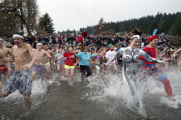 People run into the cold waters of Deep Cove in Indian Arm, North Vancouver during the Penguin Plunge on New Year`s Day.