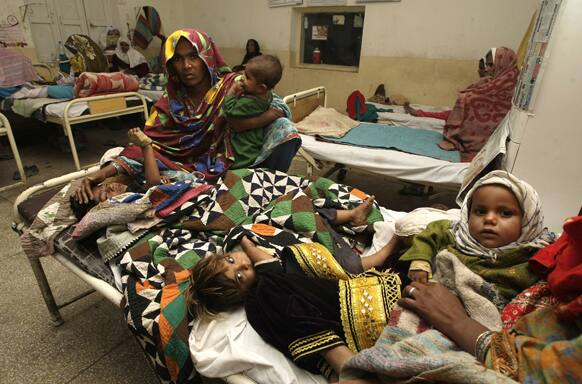 Pakistani family members hold their children suffer from measles, admitted at a local hospital in Sukkar, Pakistan.