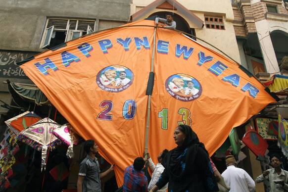 An Indian Muslim woman walks past as others prepares to hang a huge kite on top of a building ahead of a kite festival in Ahmadabad.