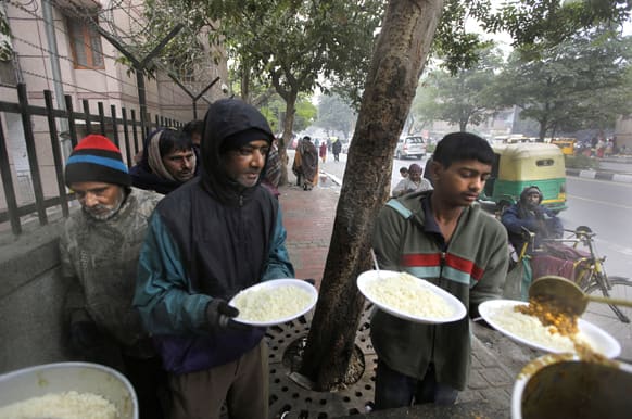 Homeless people receive free food from a voluntary organization outside a temple, in New Delhi. There are over 300,000 homeless people in New Delhi, living on the streets, braving extreme weather and economic hardship, according to news reports.