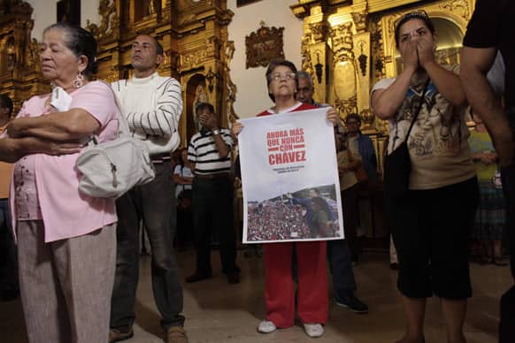 People, one of them holding an image of Venezuela`s President Hugo Chavez That reads in Spanish