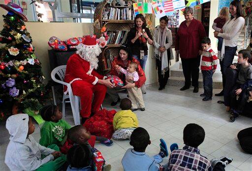 A man dressed as Santa Claus gives a present to one year old Mara from Romania, during a special 