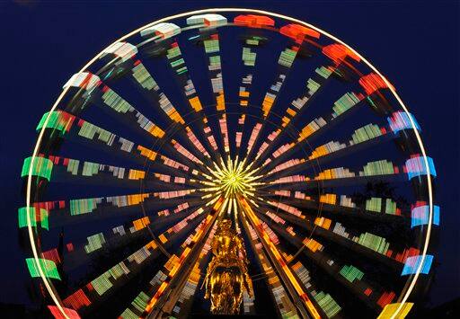 A ferris wheel on a Christmas market in Dresden, eastern Germany, turns behind the monument for Saxony's former King August the Strong, a Dresden landmark commonly known as the 