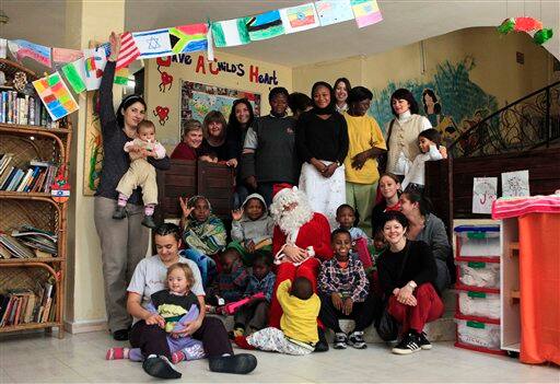 A man dressed as Santa Claus, sits with carious children waiting for medical treatment and wives of foreign diplomatic staff who work as volunteers as they pose for a group photo during a special 