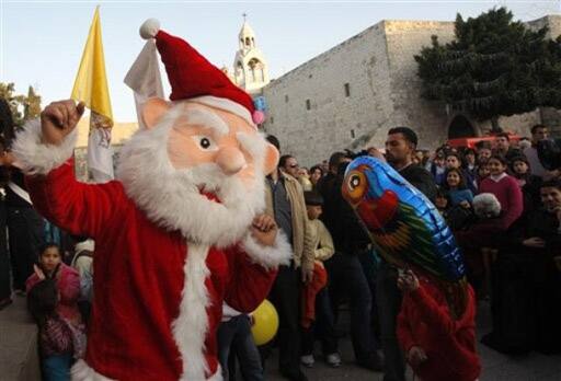 A Palestinian man dressed as Santa Claus dances at a pre-Christmas fair held just outside the Church of Nativity, Bethlehem.