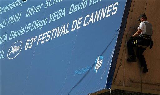 A worker sets up a giant canvas of the 63rd Cannes Film Festival's official poster on the Cannes Festival Palace