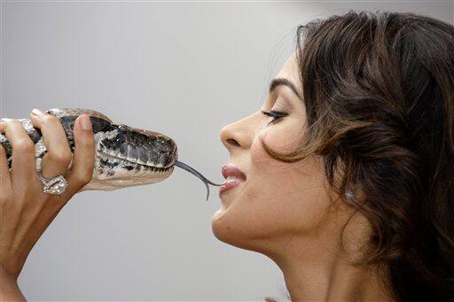 Actress Mallika Sherawat poses with a snake during a photo call for 