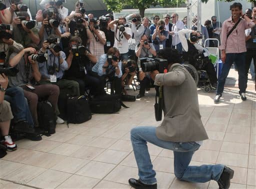 Actor Jamel Debbouze uses a photographer's camera to take pictures during a photo call for the film 