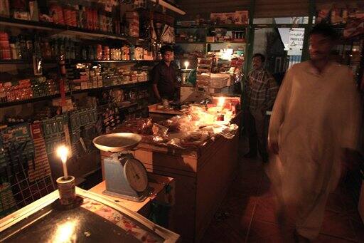 Due to power outage, a shopkeeper serves his customers under the light of candles in Sharjah, UAE