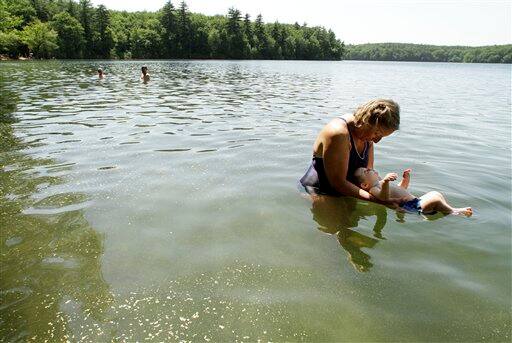 Tarun Fehsenfeld, of Acton, Mass., supports 10-month-old Elliot in the water at Walden Pond, in Concord, Mass.