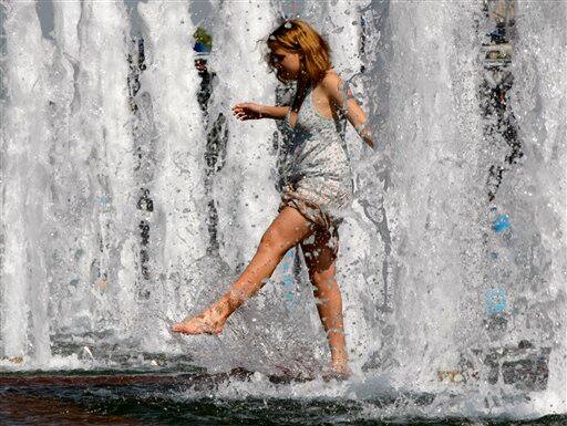 A young woman enjoys the spray from a fountain in downtown Moscow.