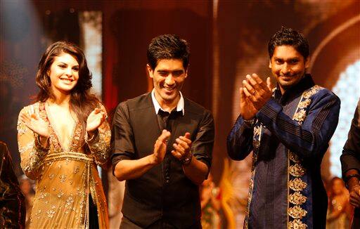 Sri Lankan Captain Kumar Sangakkara , right, and Sri Lankan born Bollywood actress Jacqueline Fernandez showcase a design from Indian designer Manish Malhothra, center, during a fashion show as part of the three-day long International Indian Film Academy (IIFA) awards in Colombo, Sri Lanka.