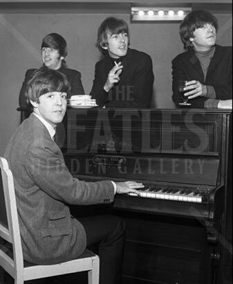 Paul sits playing the piano as Ringo, George and John lean on the top.