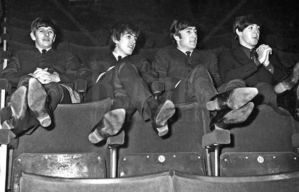 Ringo, George, John and Paul take some time out, sitting in the theatre seats with their feet up on the seat.