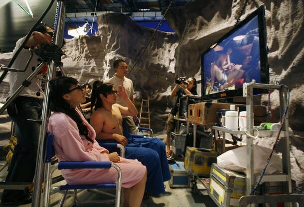 Japanese adult actress Saori Hara (2nd L) and actor Hayama Hiro (3rd L), both wearing 3D glasses, along with director Christopher Sun (4th L), watch a replay of their acting during the making of 