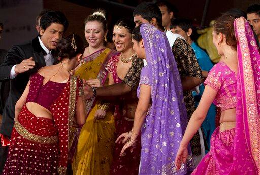 Indian actor Shah Rukh Khan, left, is greeted by dancers as he arrives on the red carpet to attend the screening of his movie 