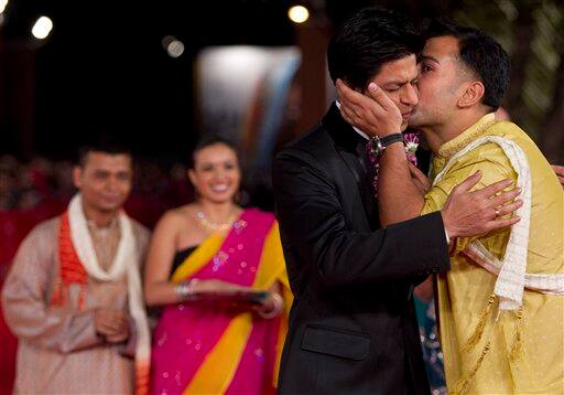 Indian actor Shah Rukh Khan, left, is kissed by a fan as he arrives on the red carpet of his movie 