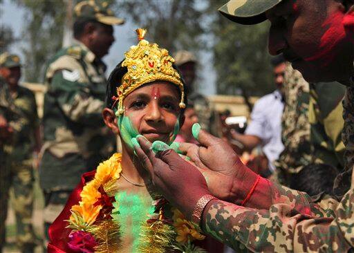 Indian Border Security Force soldiers celebrate Holi festival with a child dressed as Hindu Lord Krishna, at the India-Pakistan international border in Ranbir Singh Pura, India.