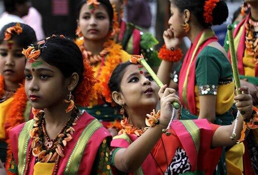 Indian girls in traditional costumes dance on a street during festivities marking holi in Calcutta.