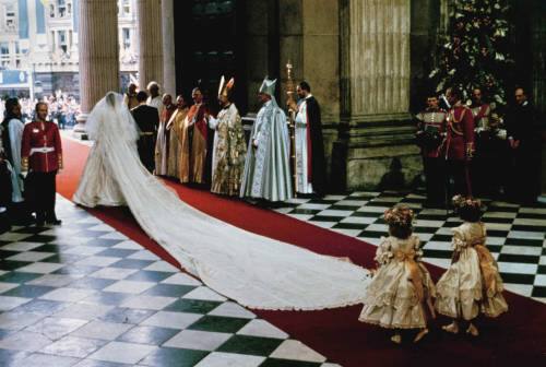 Princess Diana's long train follows her as the bride's maids look on. 