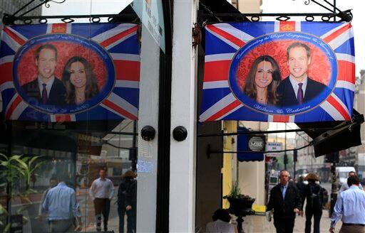 People walk by a cafe in London flying the Union flag with a central picture of Prince William and Kate Middleton.