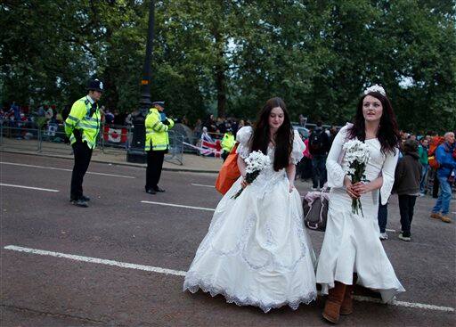 Royal enthusiasts Molly Thorne, right, and Clarissa Marston, left, from Bedford, UK, wear bridal gowns as they cross The Mall next to Buckingham Palace along the Royal Wedding route in London.