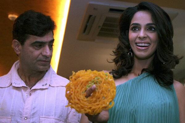 Bollywood actress Malika Sherawat  poses with director Indra Kumar after making 'jalebi' at a promotional event for the forthcoming Hindi film 'Double Dhamal' in Mumbai.