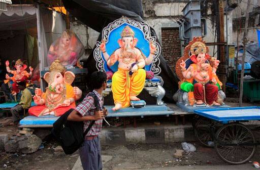 An Indian boy returning from school looks at idols of elephant-headed god Ganesh displayed for sale by a roadside ahead of Ganesh Chaturti festival in Hyderabad.