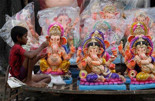 An Indian girl sits near idols of elephant headed Hindu god Ganesh displayed for sale ahead of Ganesh Chaturti festival in Ahmadabad.