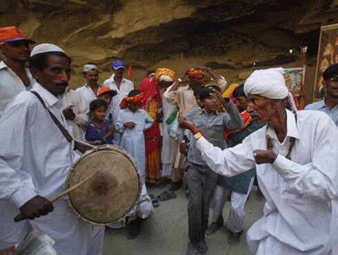 A devotee beats the dhol as the other dances to its beats.