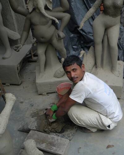 A crafstman puts mud on hay figurines at a workshop in New Delhi.