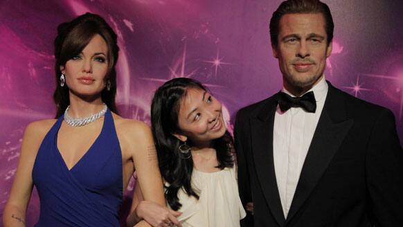 A model poses with Brad Pitt and Angelina Jolie`s wax figures at the Madame Tussauds wax exhibition in Tokyo.