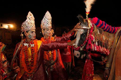 Indian artists dressed as Hindu deities Rama and Lakshmana, left, touch a horse before riding on it during a Dussehra procession in Allahabad.