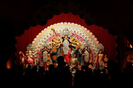 Hindu devotees offer prayers before an idol of goddess Durga, center, during the Durga Puja festival in Allahabad.