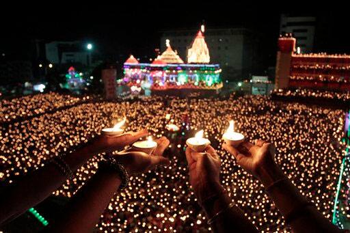 Indian devotees holds earthen lamps and take part in Maha Aarti ritual at Hindu deity Umiya Mata temple on the eighth night of Navratri or nine nights festival in Surat.